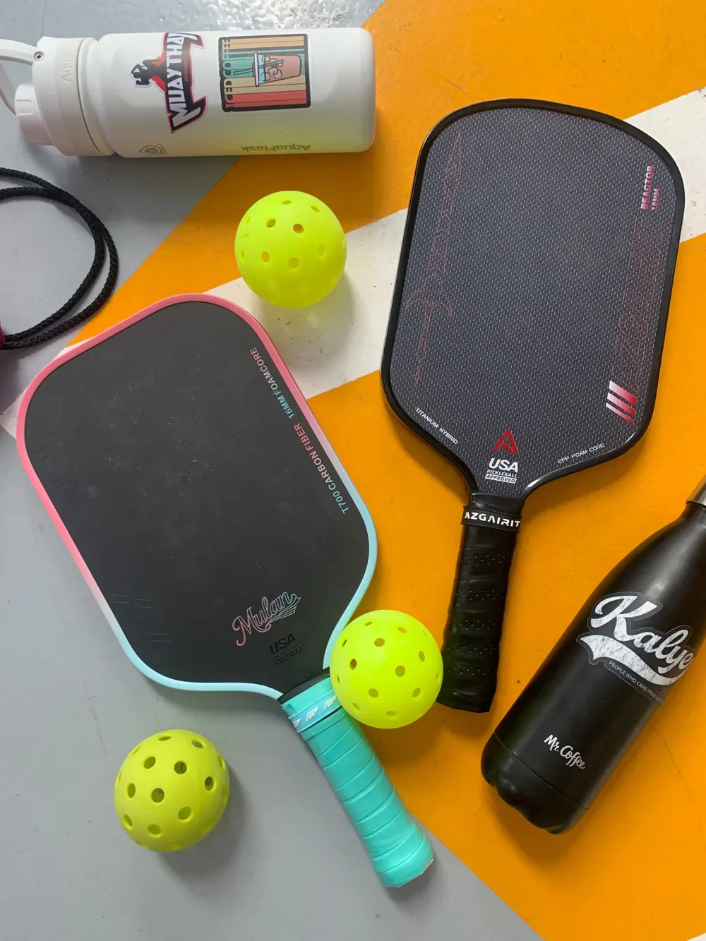 Two colorful pickleball paddles with bright yellow balls on an orange and white background
